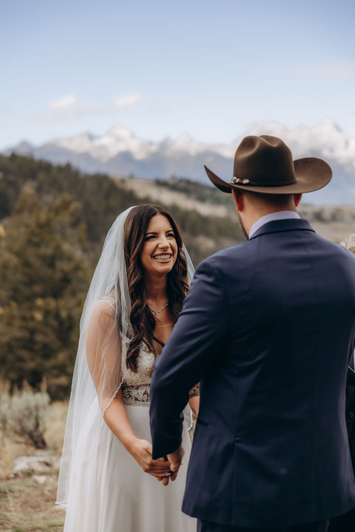 A bride and groom share intimate moments during their mountain wedding ceremony against a scenic backdrop.