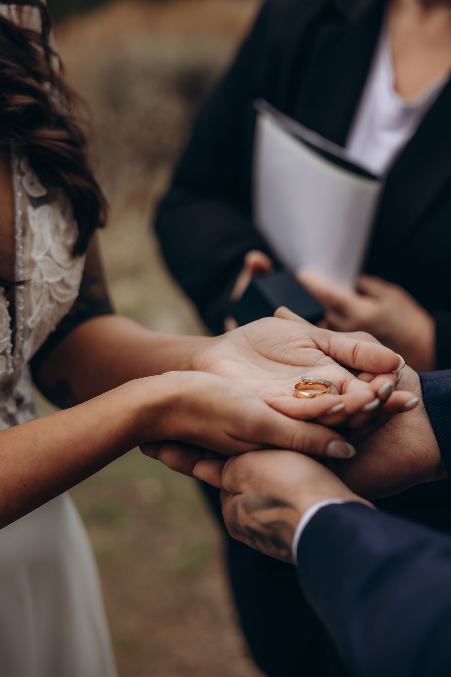 Close-up view of hands exchanging wedding rings during an intimate outdoor ceremony.