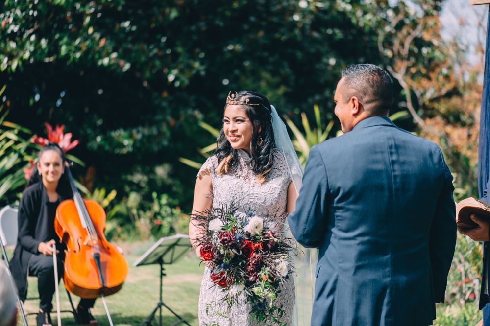 Wedding ceremony in progress at a scenic outdoor garden venue with floral arrangements.