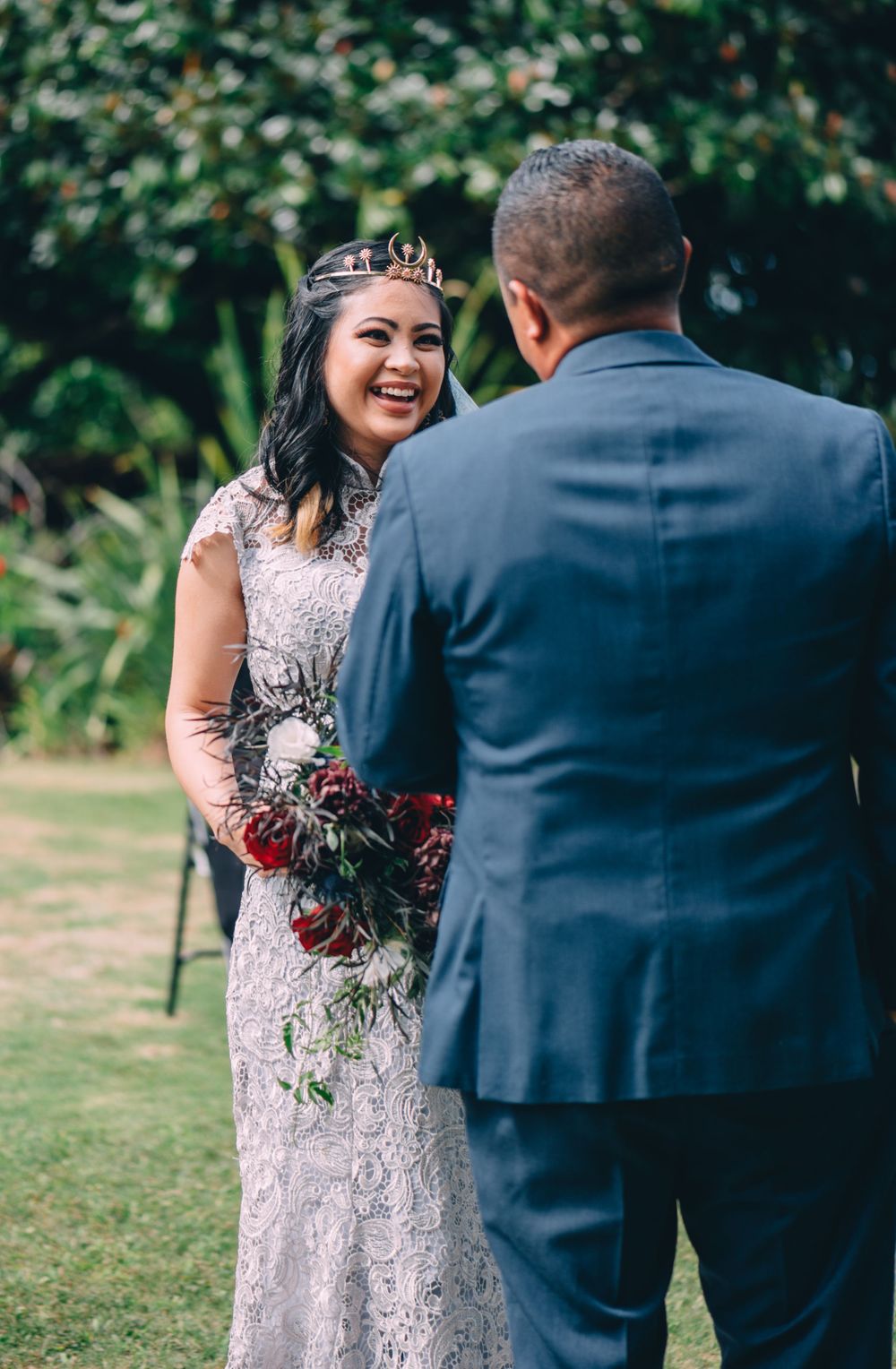 Couple exchanging vows during outdoor wedding ceremony with lush greenery backdrop.