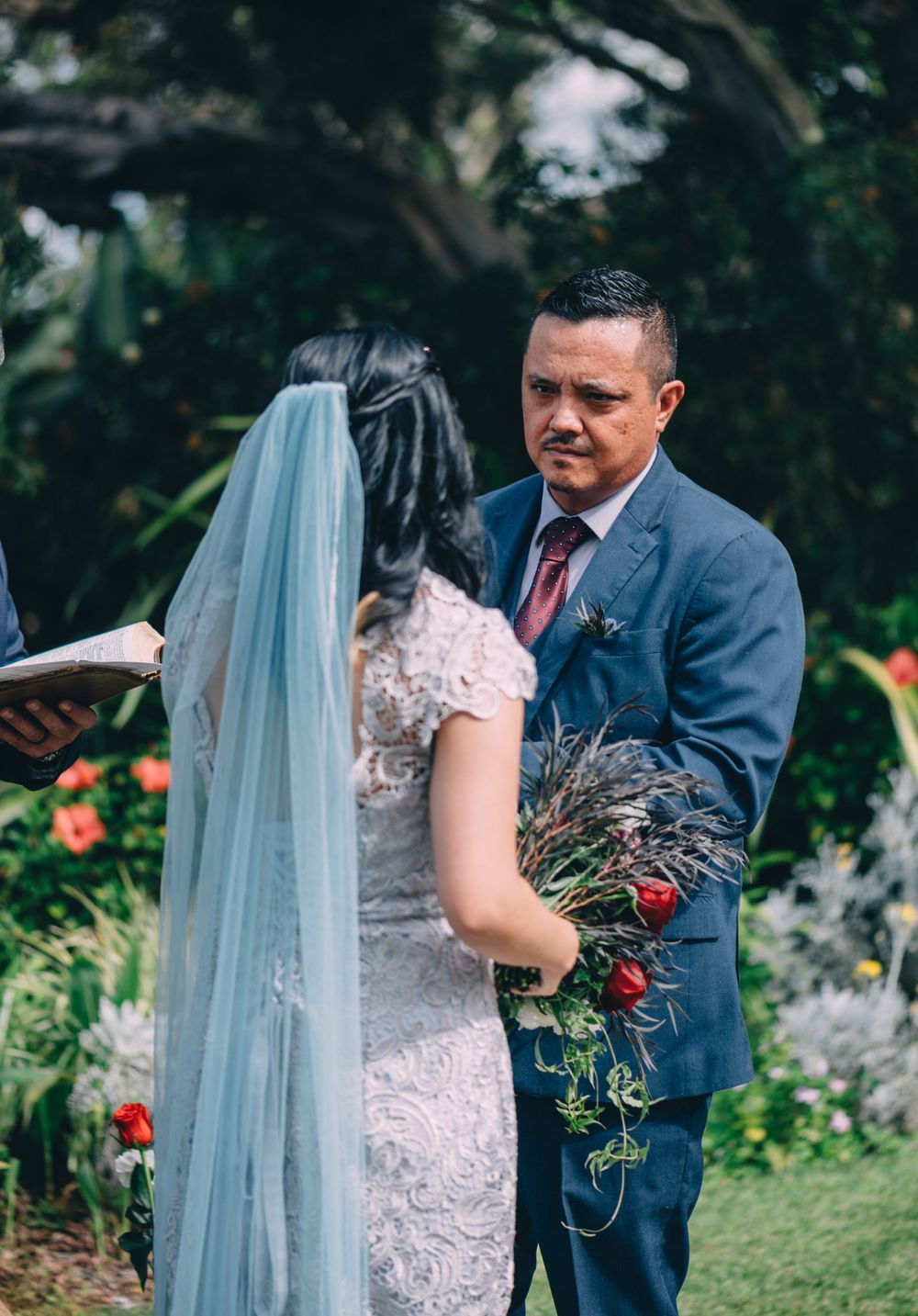 Intimate moment during wedding ceremony with couple in blue suit and lace dress.