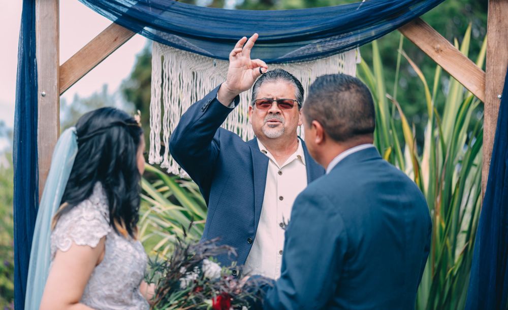 Wedding ceremony details showing wooden arch with blue fabric decor.