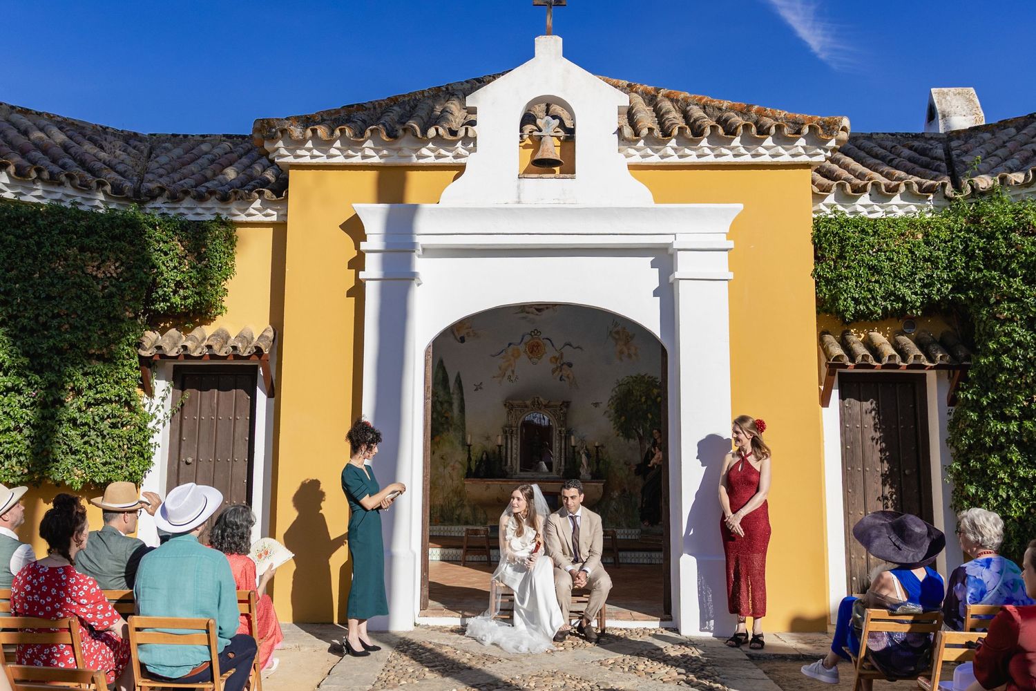 Visitors explore the historic yellow-walled courtyard with white archways at a Spanish colonial hacienda.