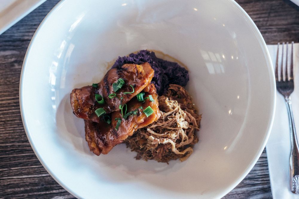 Elegant plating of grilled meats and seafood on white dishes against a rustic wooden table.