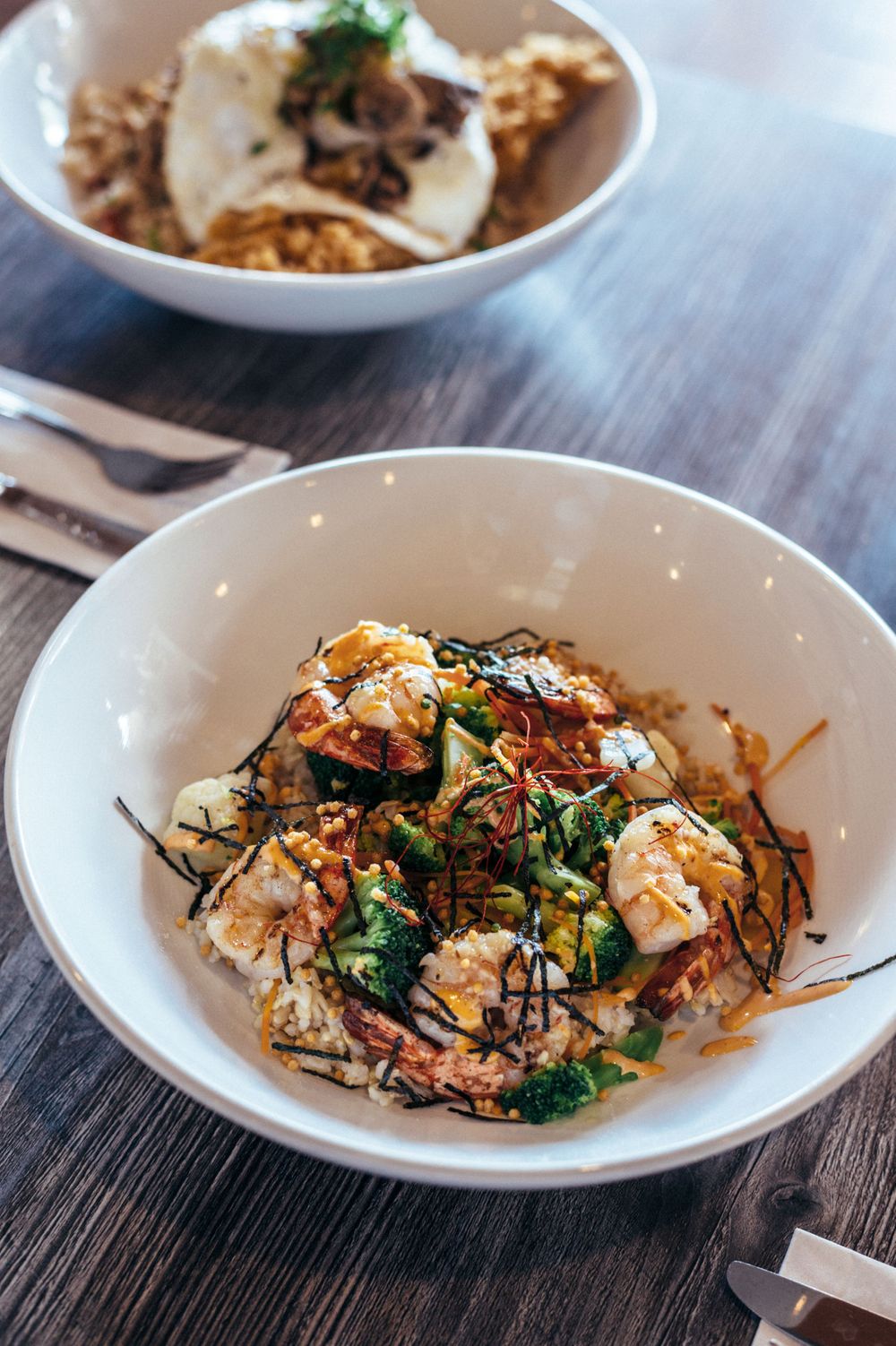 Asian-inspired rice bowls with mixed vegetables and proteins in white ceramic dishes.