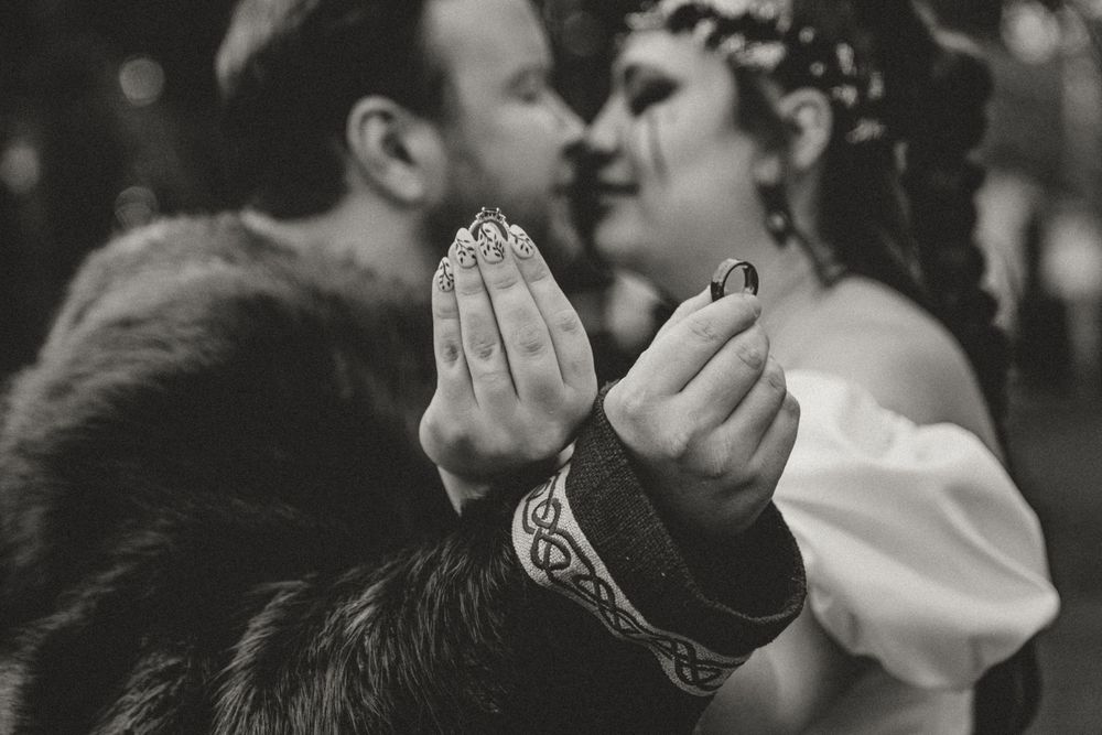 Black and white photo of a Viking-themed wedding couple kissing, showcasing Celtic bracelet and ring exchange.