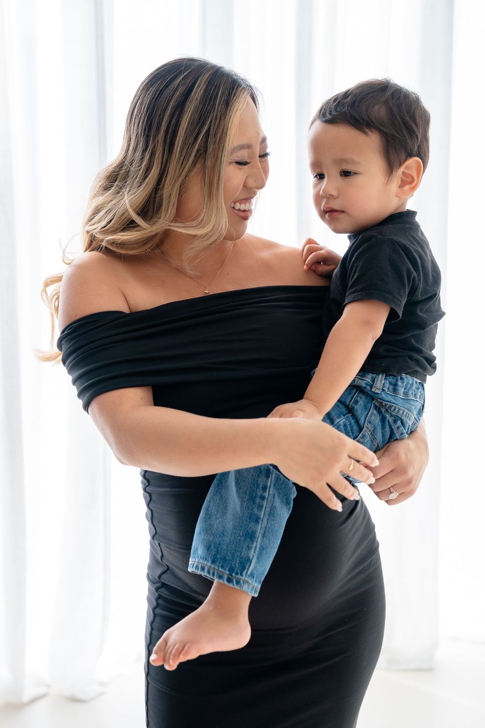 A mother in black dress holds and plays with a baby wearing denim, shown in a series of candid moments.