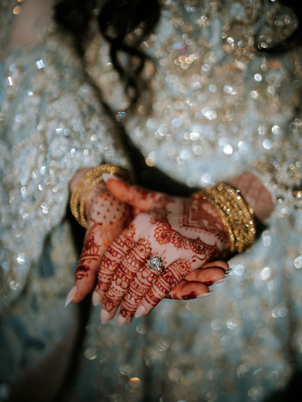 Close-up shots of traditional henna designs on hands with sparkling decor in background.