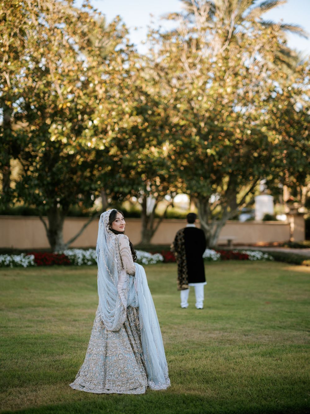 Stunning bridal portraits in white and silver lehenga against a lush garden backdrop.