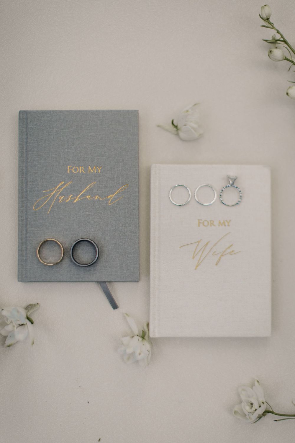Wedding stationery and rings styled in soft blue and white with gold lettering.