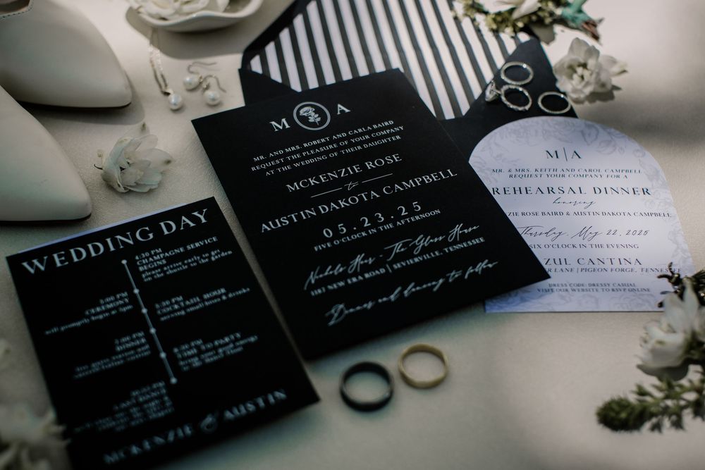 Modern black and white wedding stationery with rings and floral accents.
