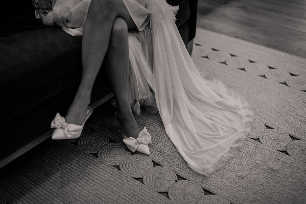 Black and white image showing details of a wedding dress and shoes.