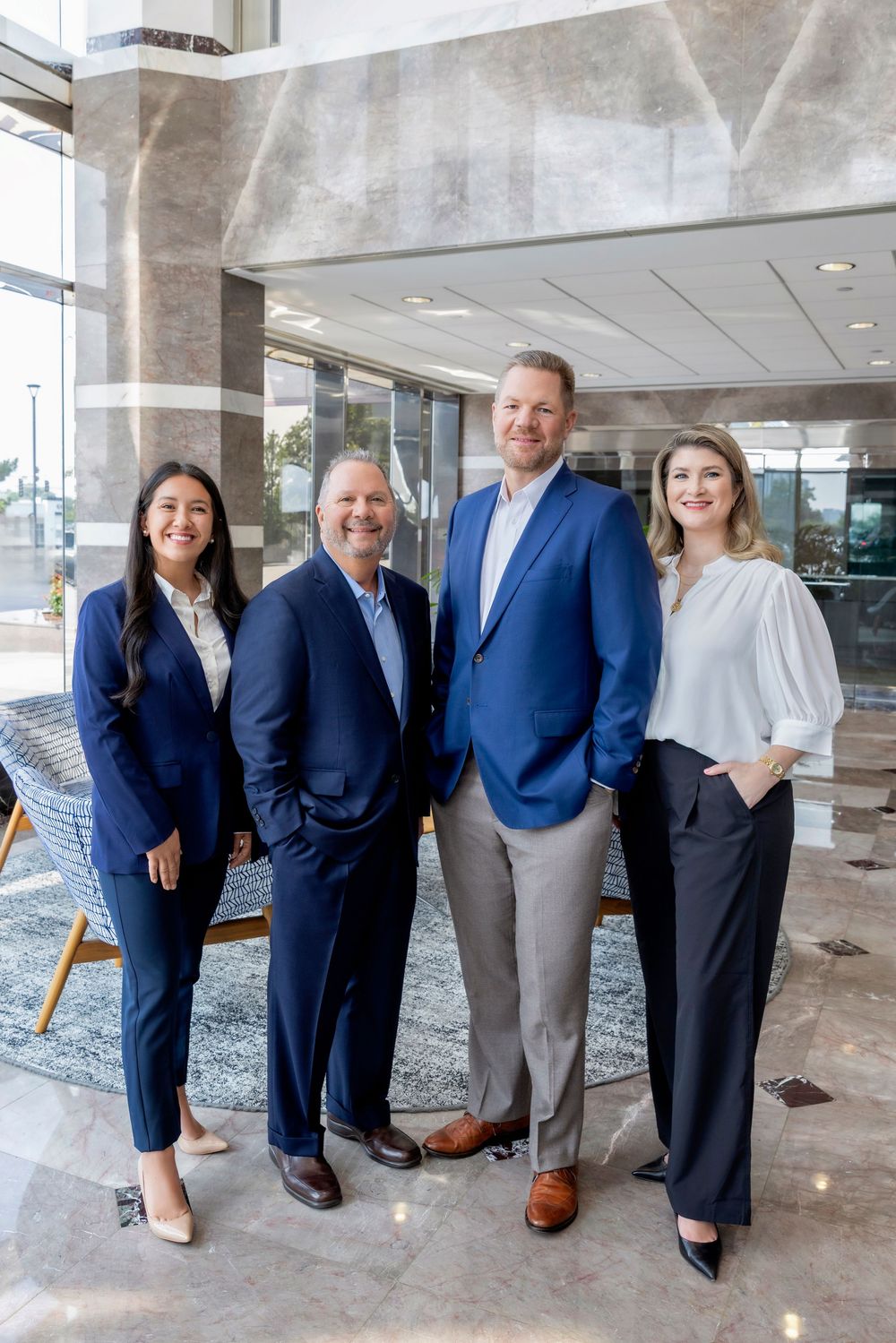 Professional business team in navy suits poses together in modern office lobby.