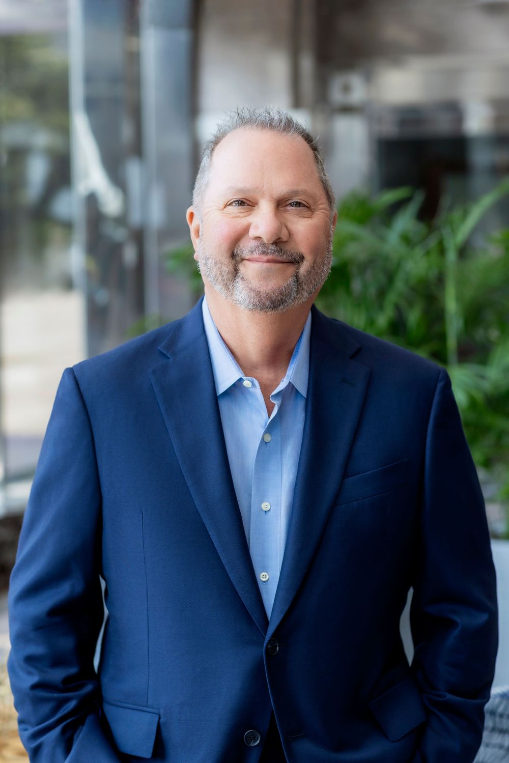 Executive wearing navy blazer and light blue shirt photographed in corporate headshots.
