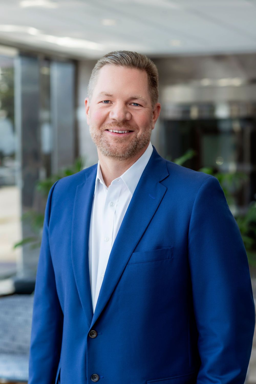 Professional headshot series showing person in blue suit and white shirt against modern office background.