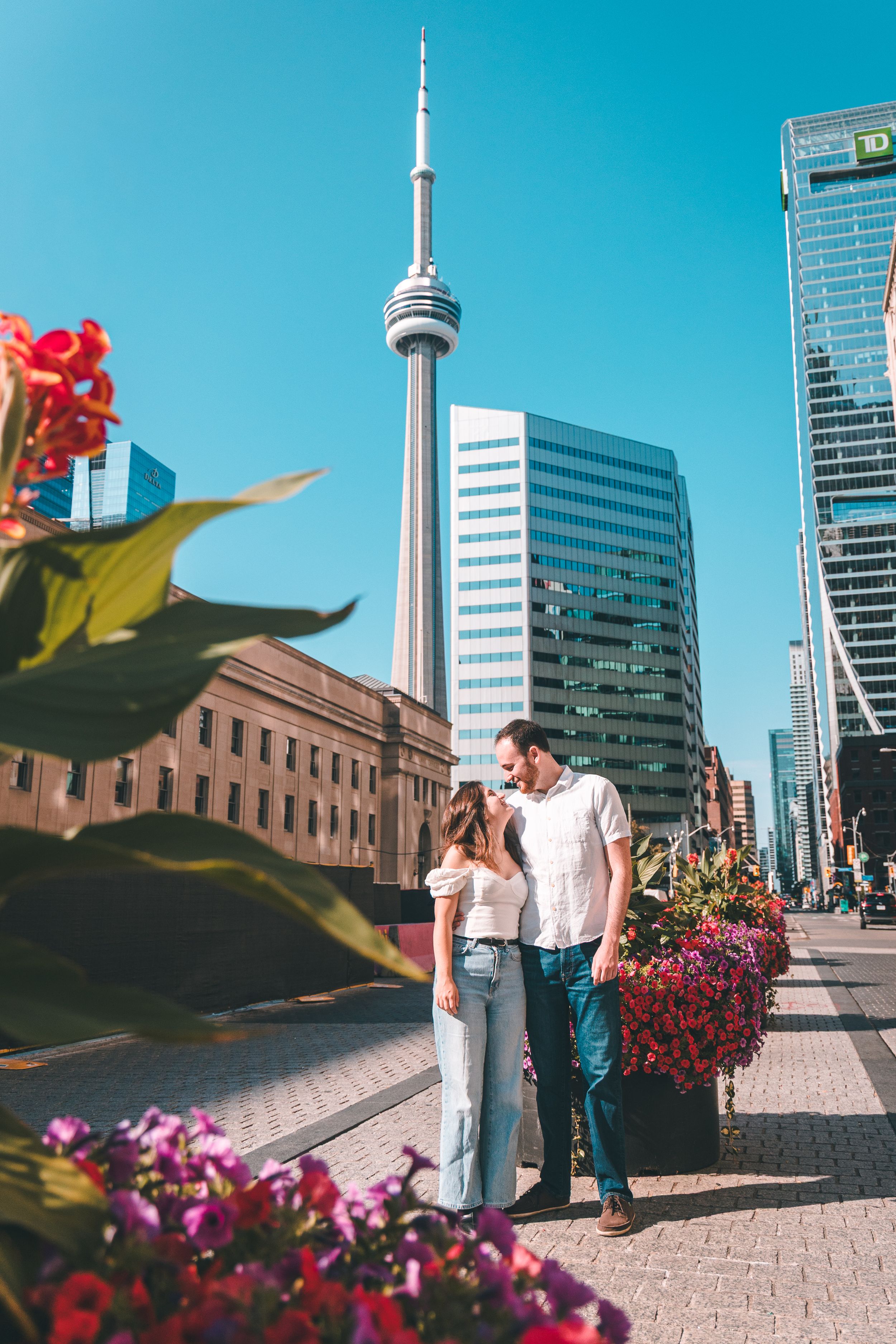 A series of romantic photos with the CN Tower and Toronto skyline in the background, surrounded by colorful flowers.