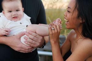 A tender moment between parent and baby outdoors in warm sunlight.