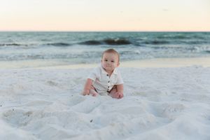 A collage of beach photos showing a baby playing in white sand near ocean waves.