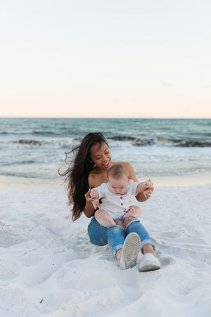 A tender moment shared between parent and child playing together on a pristine white sandy beach at sunset.