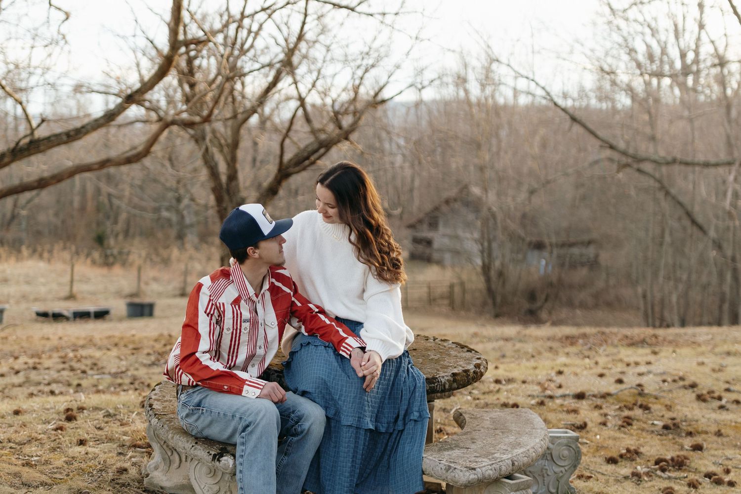 A couple shares an intimate moment in a rustic outdoor setting during golden hour.
