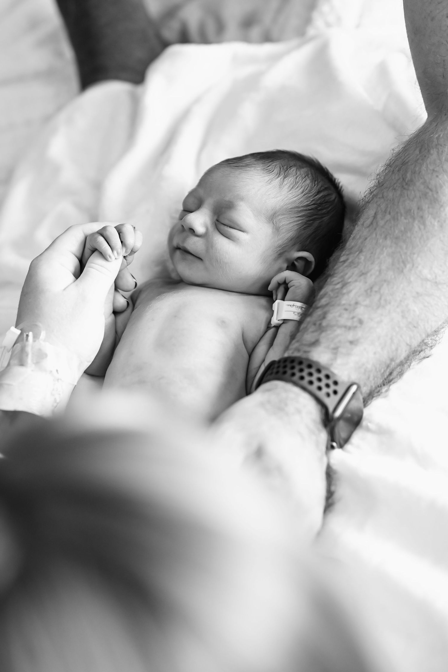 Close-up black and white photo of newborn baby sleeping on blanket.