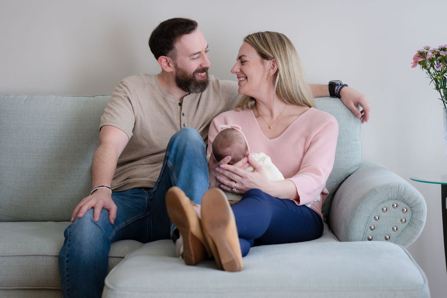 Happy couple relaxing on couch at home with their newborn baby.