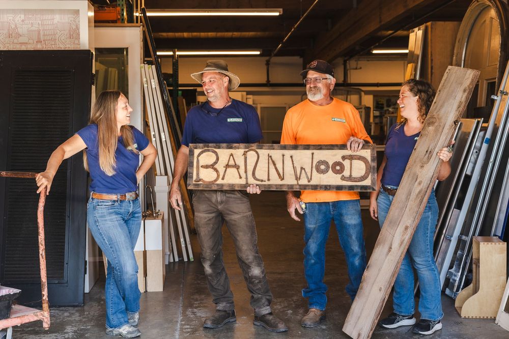 Workers move building materials and supplies inside a dimly lit warehouse space.