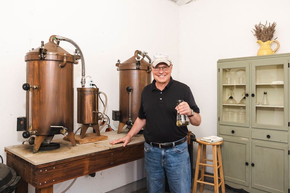 Copper moonshine still setup with multiple glass jars and distilling equipment arranged in a rustic workshop setting.