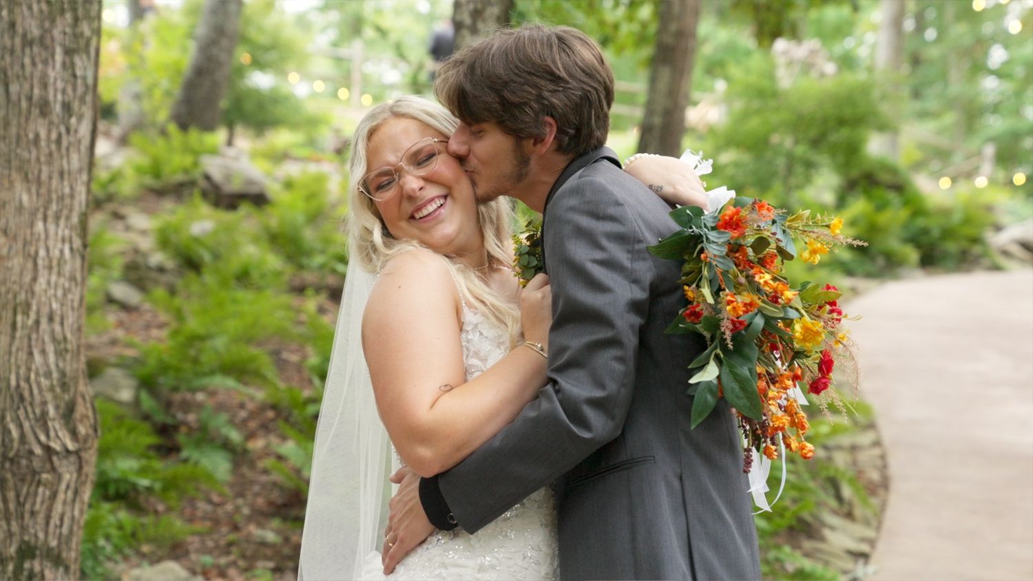 Romantic couple embraces in a lush garden setting surrounded by greenery and natural light.