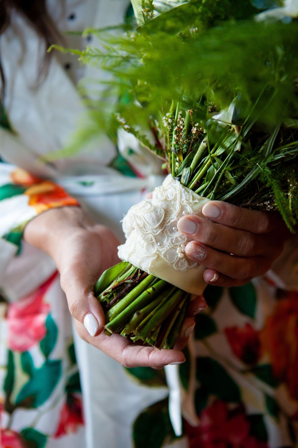 Close-up sequence showing hands delicately holding and arranging a white floral bouquet with greenery.