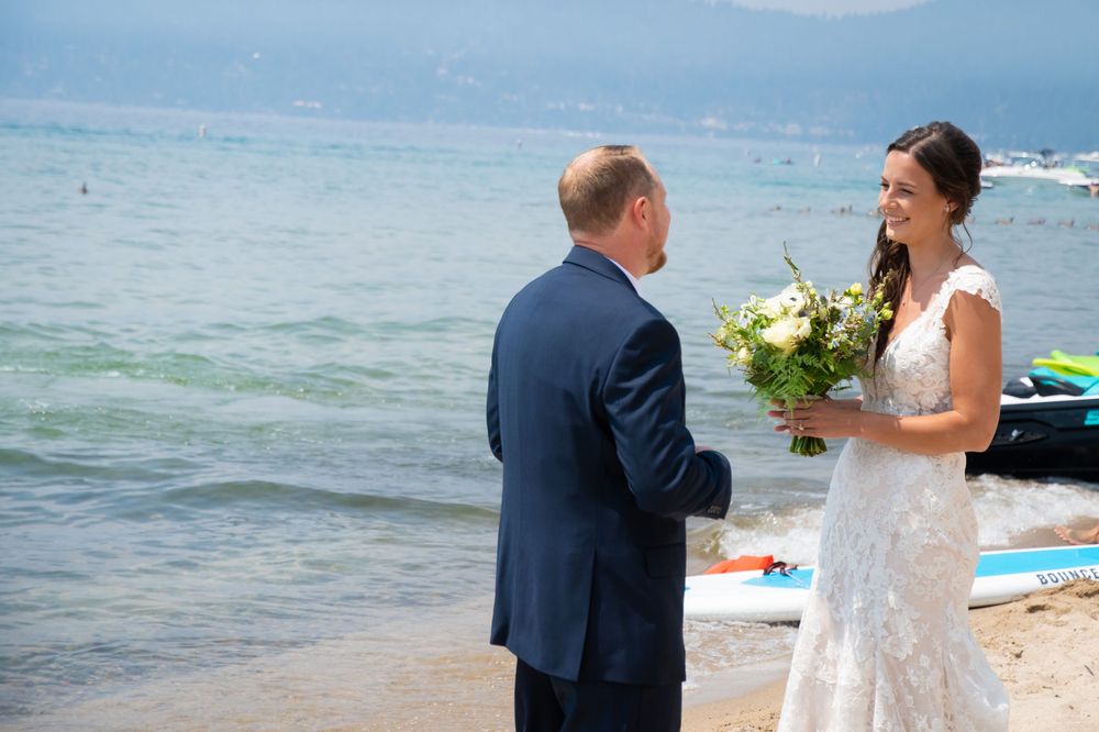 A beachside wedding ceremony with ocean and mountains in background.