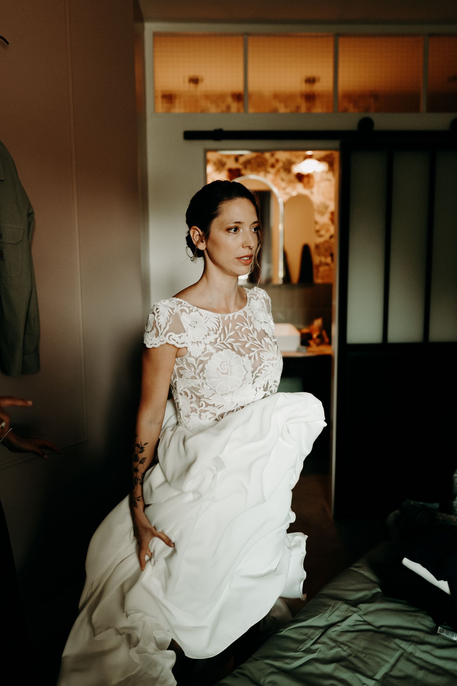 Elegant wedding dress with dramatic cathedral-length lace veil captured in warm, moody lighting inside historic venue.
