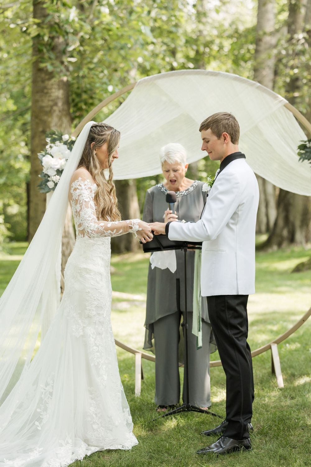 Outdoor wedding ceremony with flowing white dress and veil in natural setting.