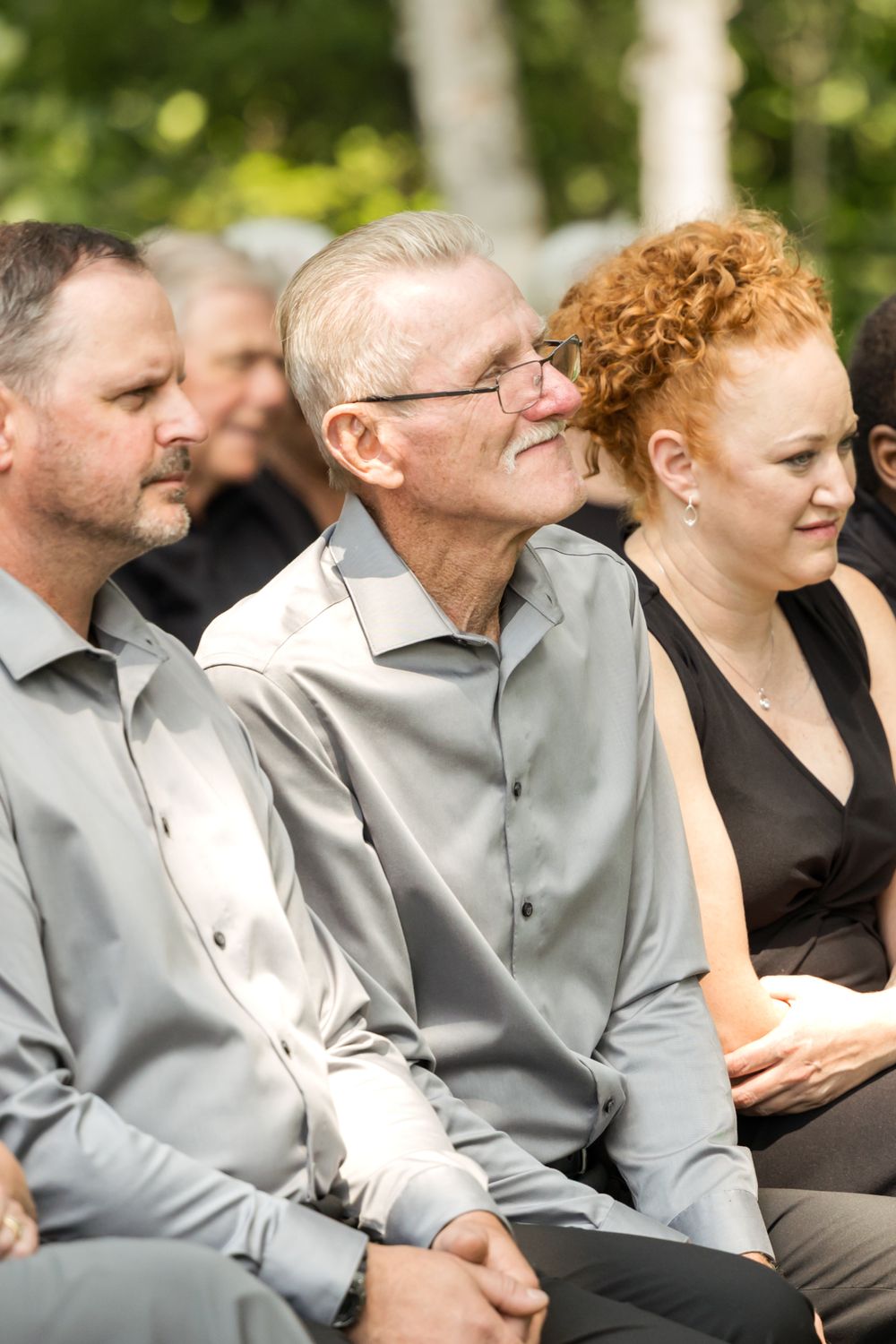 Wedding attendees in formal attire watch ceremony with joyful expressions.
