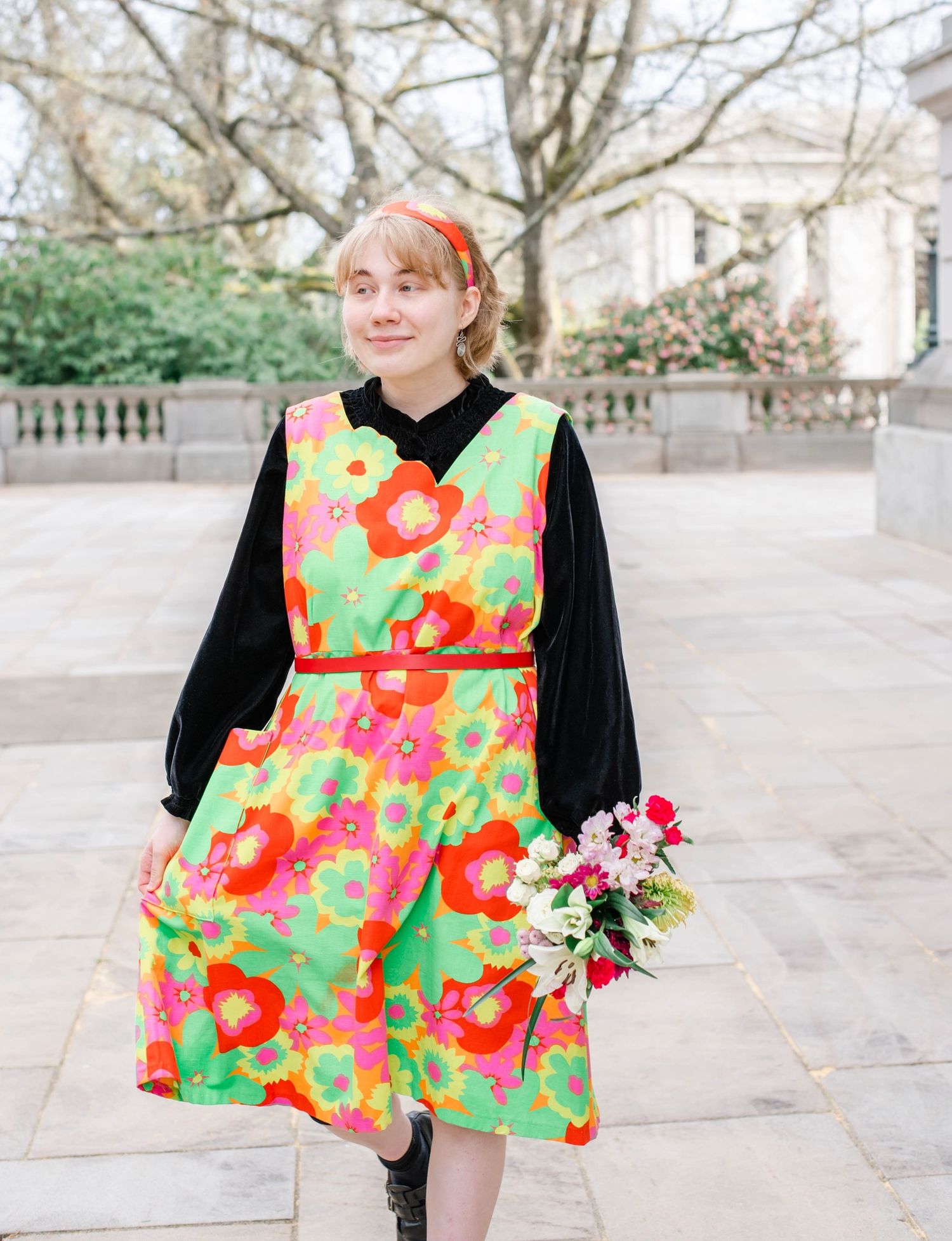 A bright floral print dress in green, pink and orange is displayed in multiple views against a light outdoor background.
