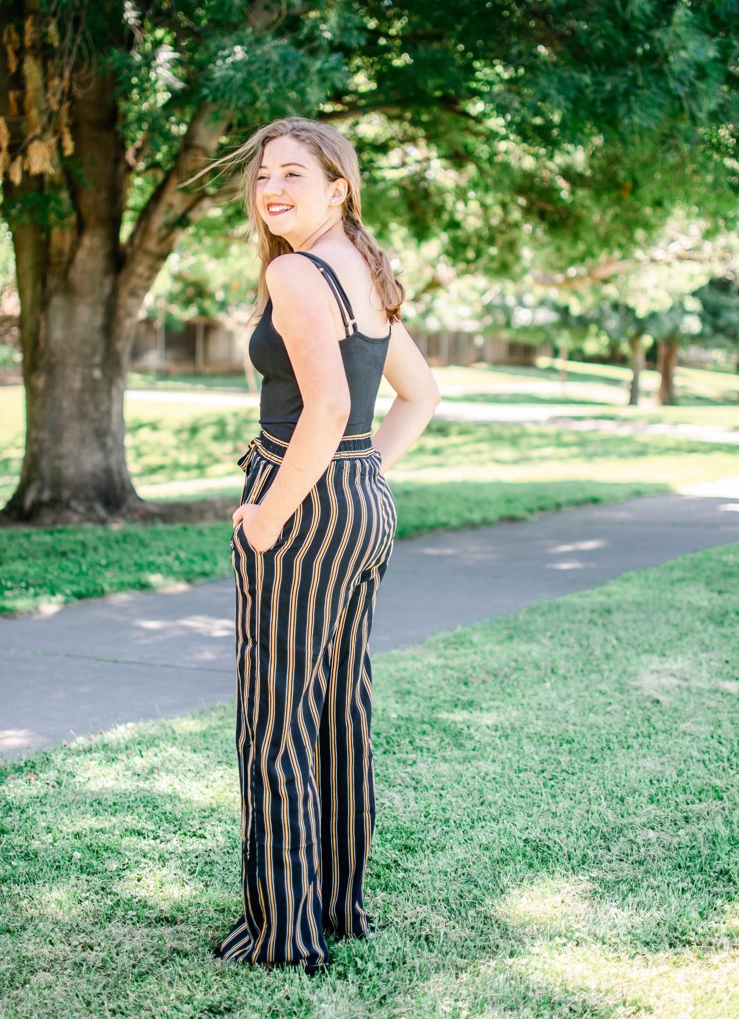 A series of photos showing a person in a black and tan striped maxi dress posing outdoors in a park setting.