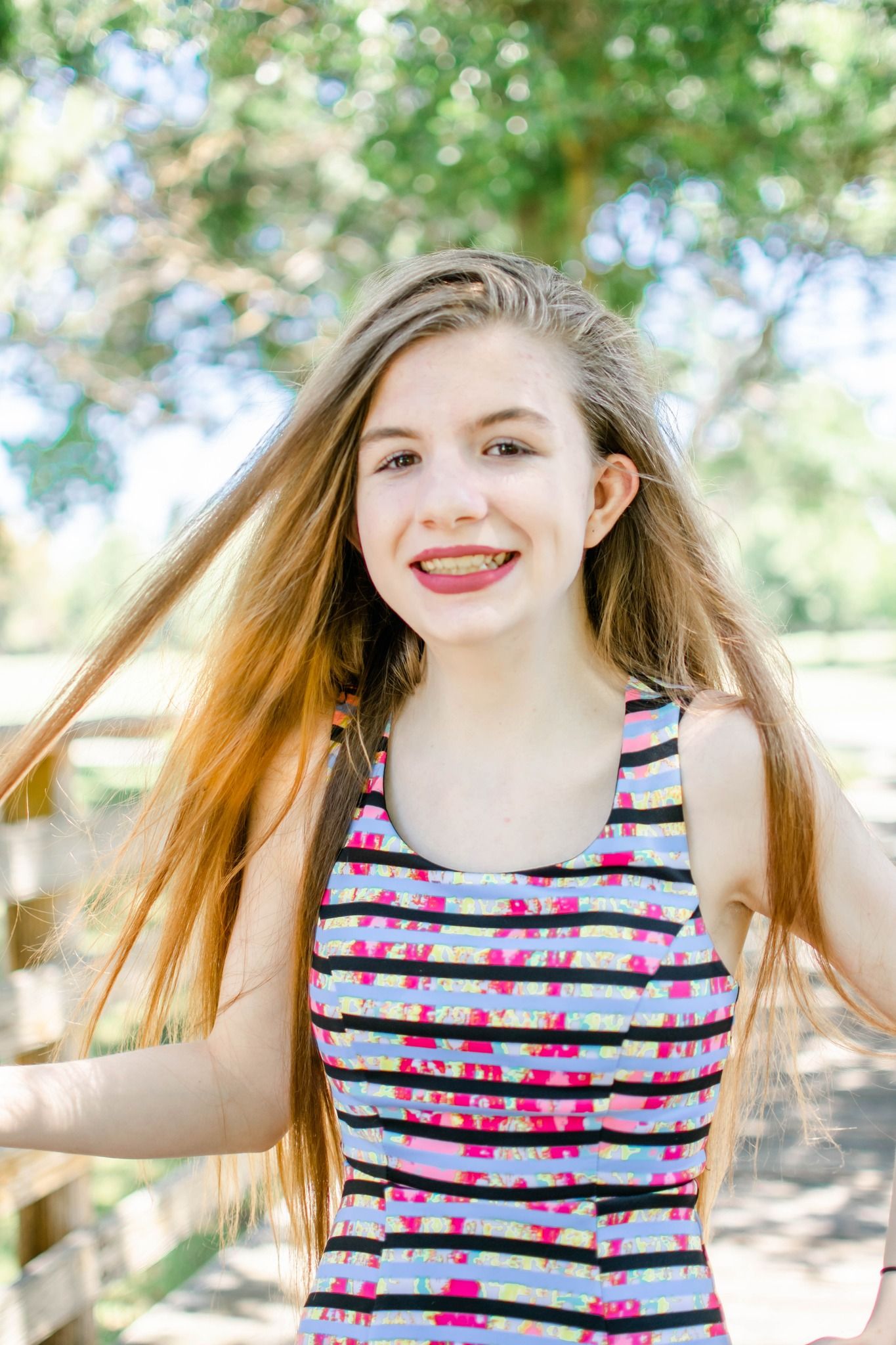 A series of four outdoor portraits showing joyful expressions and flowing hair movement in a striped floral dress.