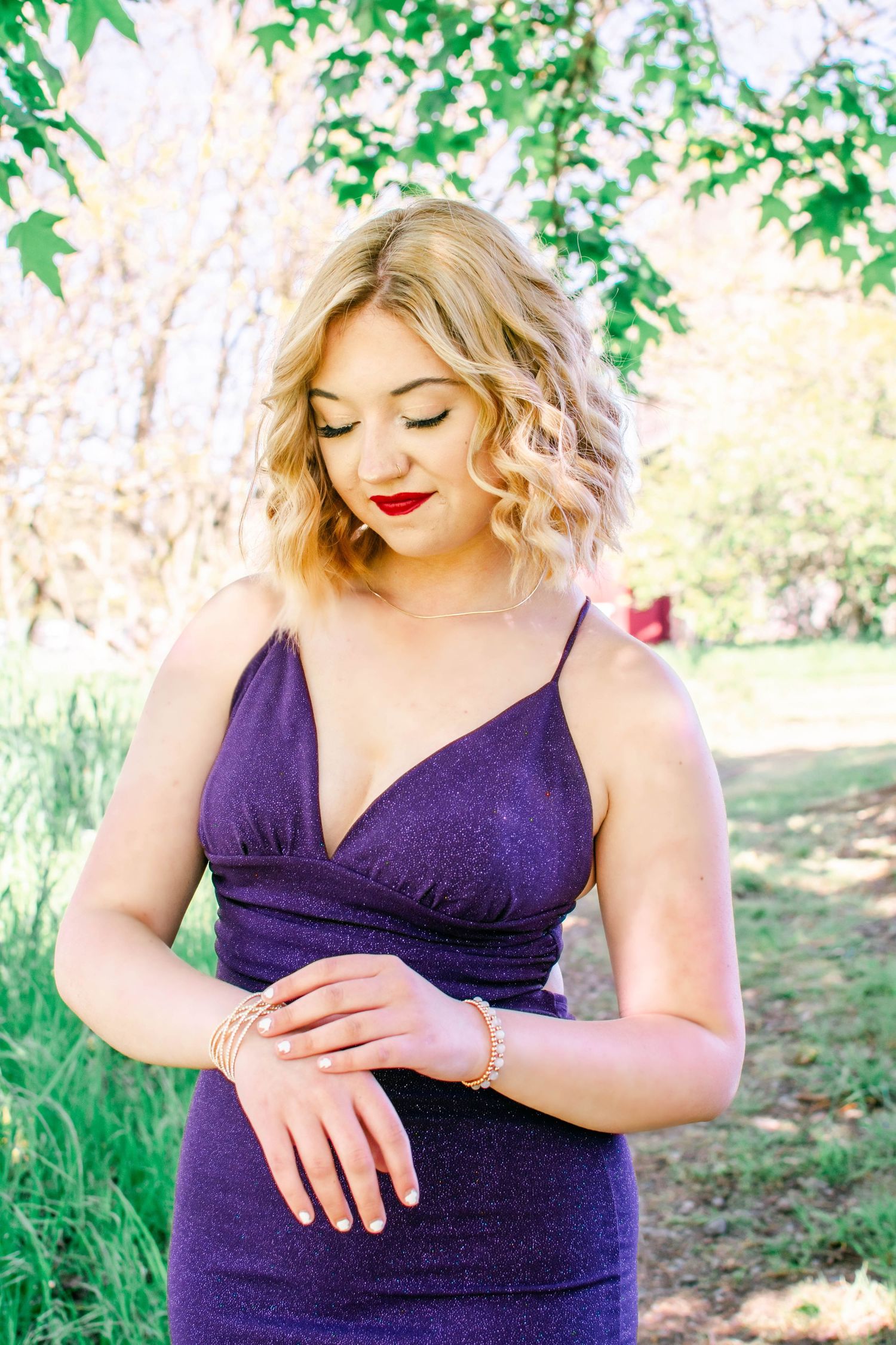 A woman in a deep purple dress poses outdoors in a series of cropped photos showing her torso and hands.