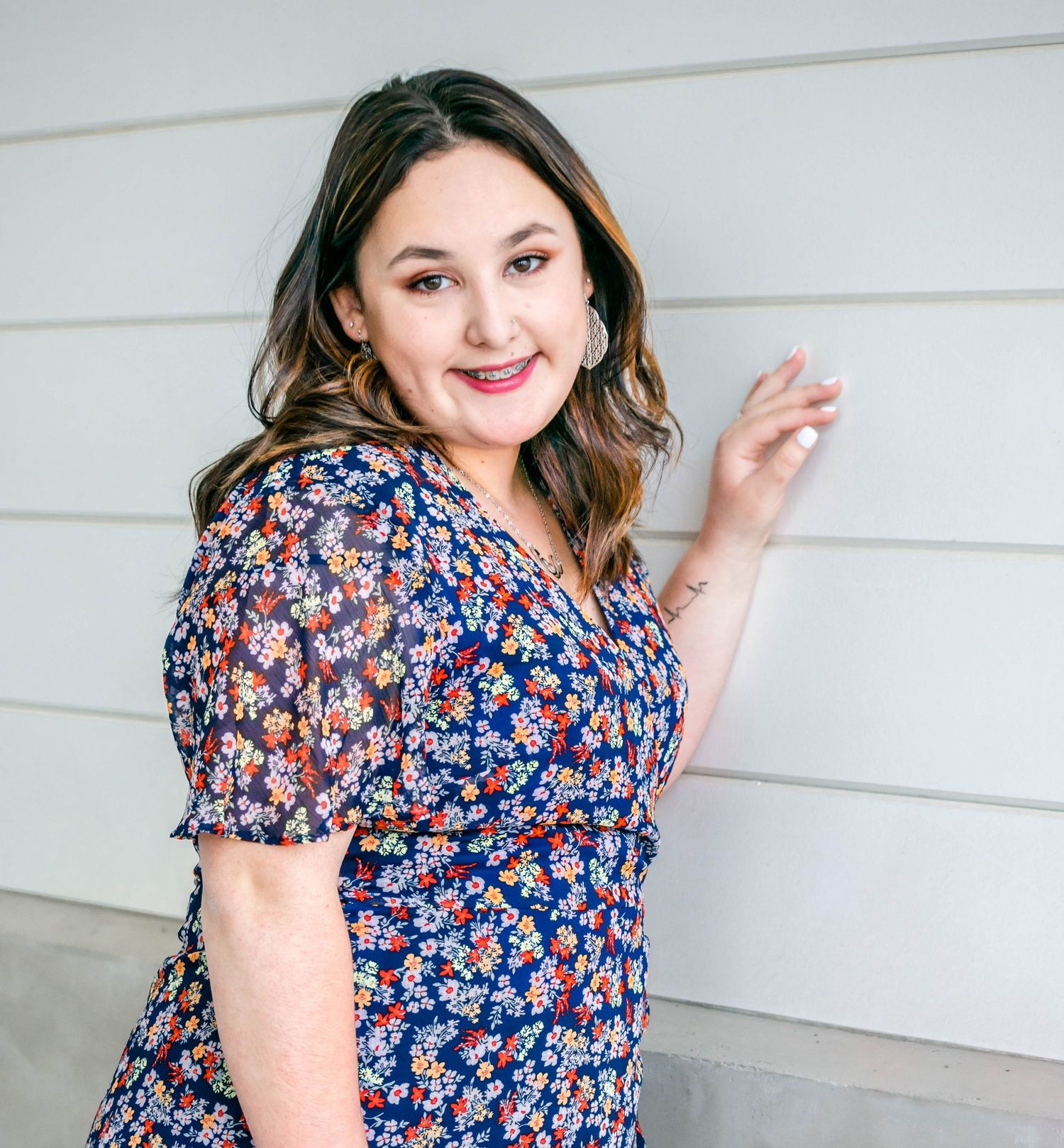 Woman in floral print dress poses against white wall with playful expressions in multi-frame photo series.