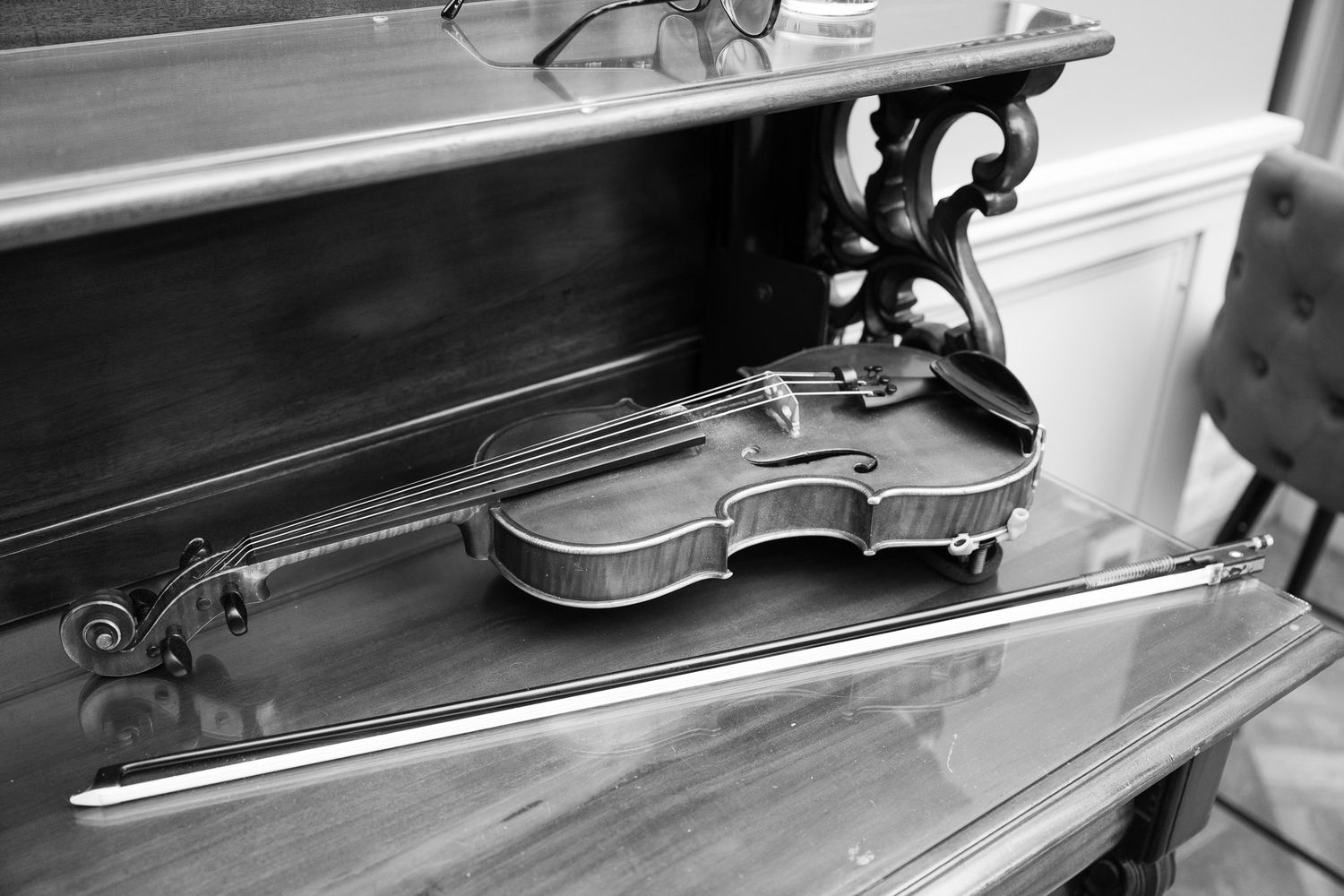 Violin maker's workbench with tools and wooden instrument parts laid out in black and white photograph.