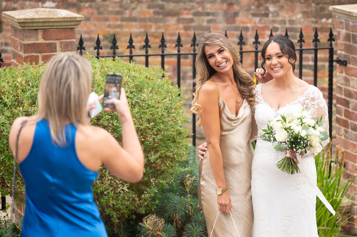 A candid wedding photography sequence showing a bride and bridesmaids laughing together in a garden setting.