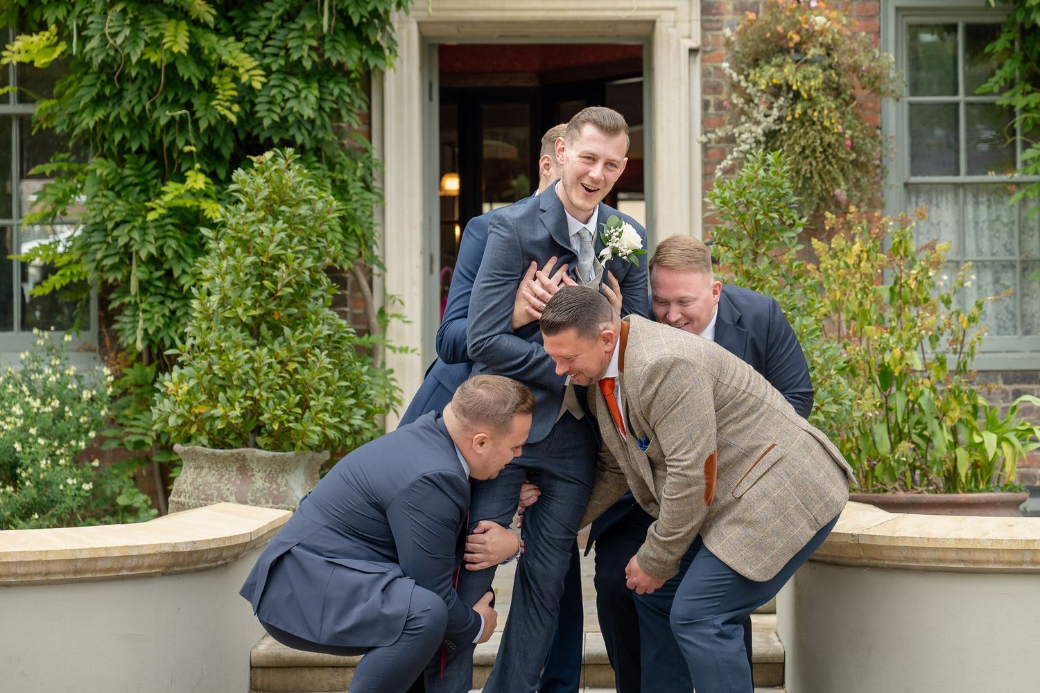 A series of five candid photos showing two people hugging and embracing on a front porch with green foliage.