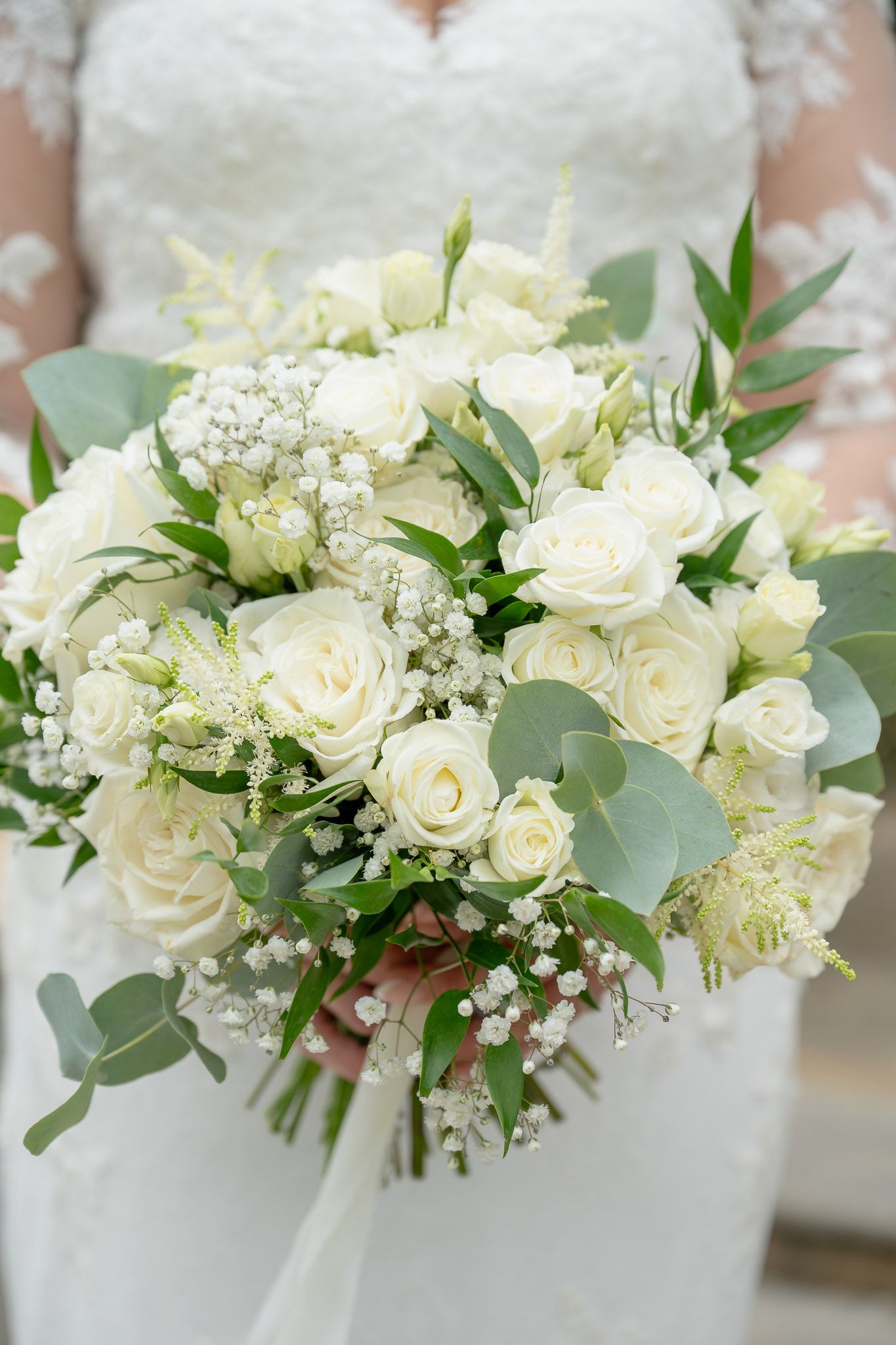 Close-up views of elegant white rose and baby's breath wedding bouquets with eucalyptus greenery against a light background.