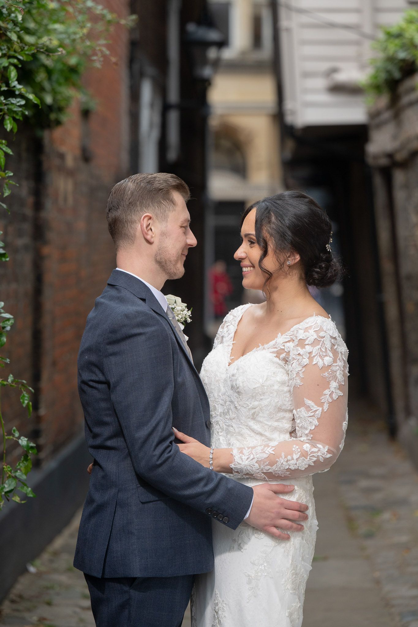 A couple shares joyful moments in a sequence of candid wedding photos along a charming brick alleyway.