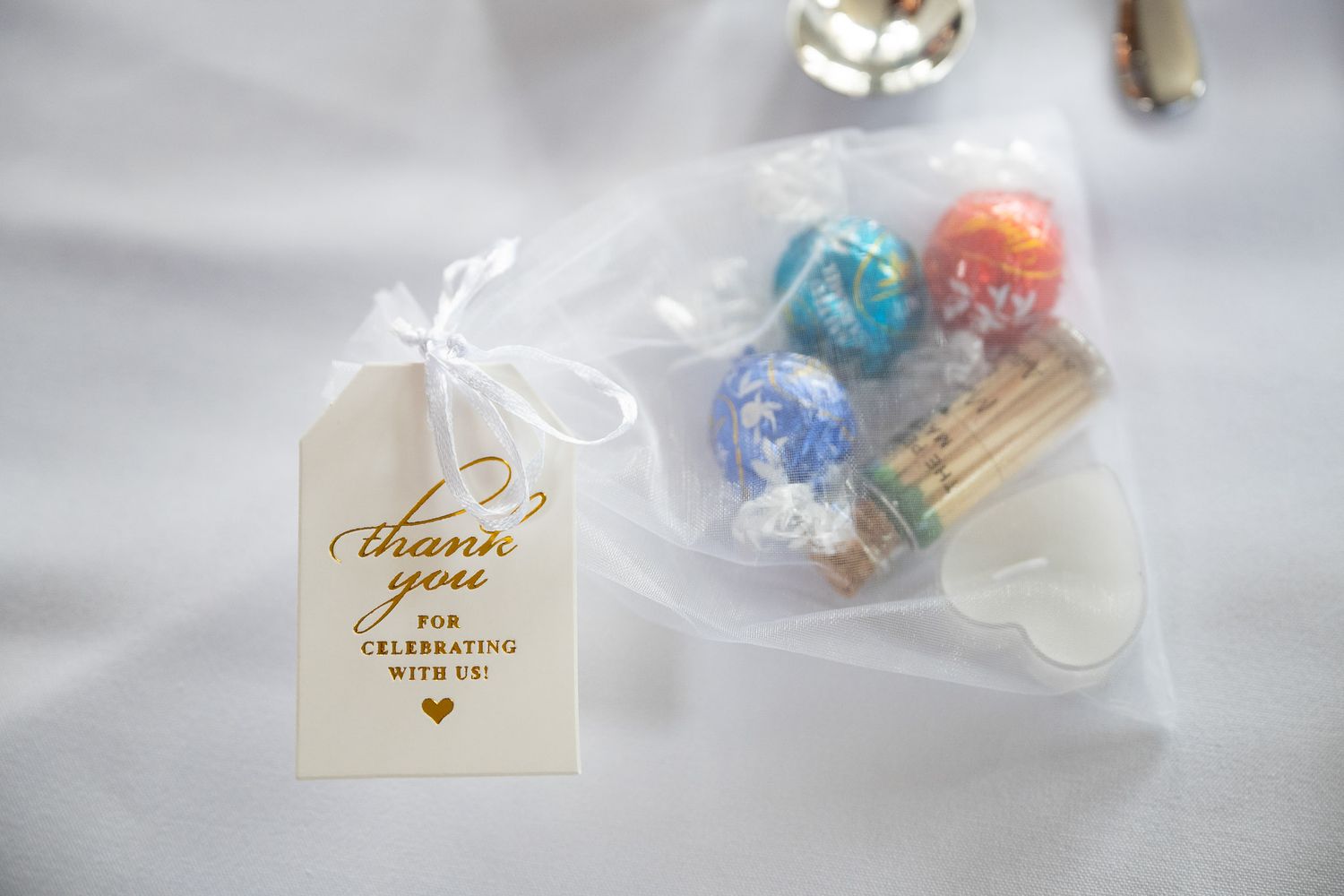 Small decorative thank you tags and gift wrapping supplies arranged on a soft white background.
