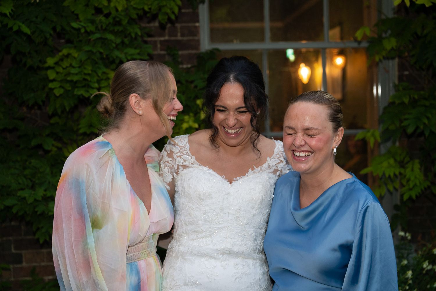 A group of people in formal attire share joyful moments at an outdoor wedding celebration.
