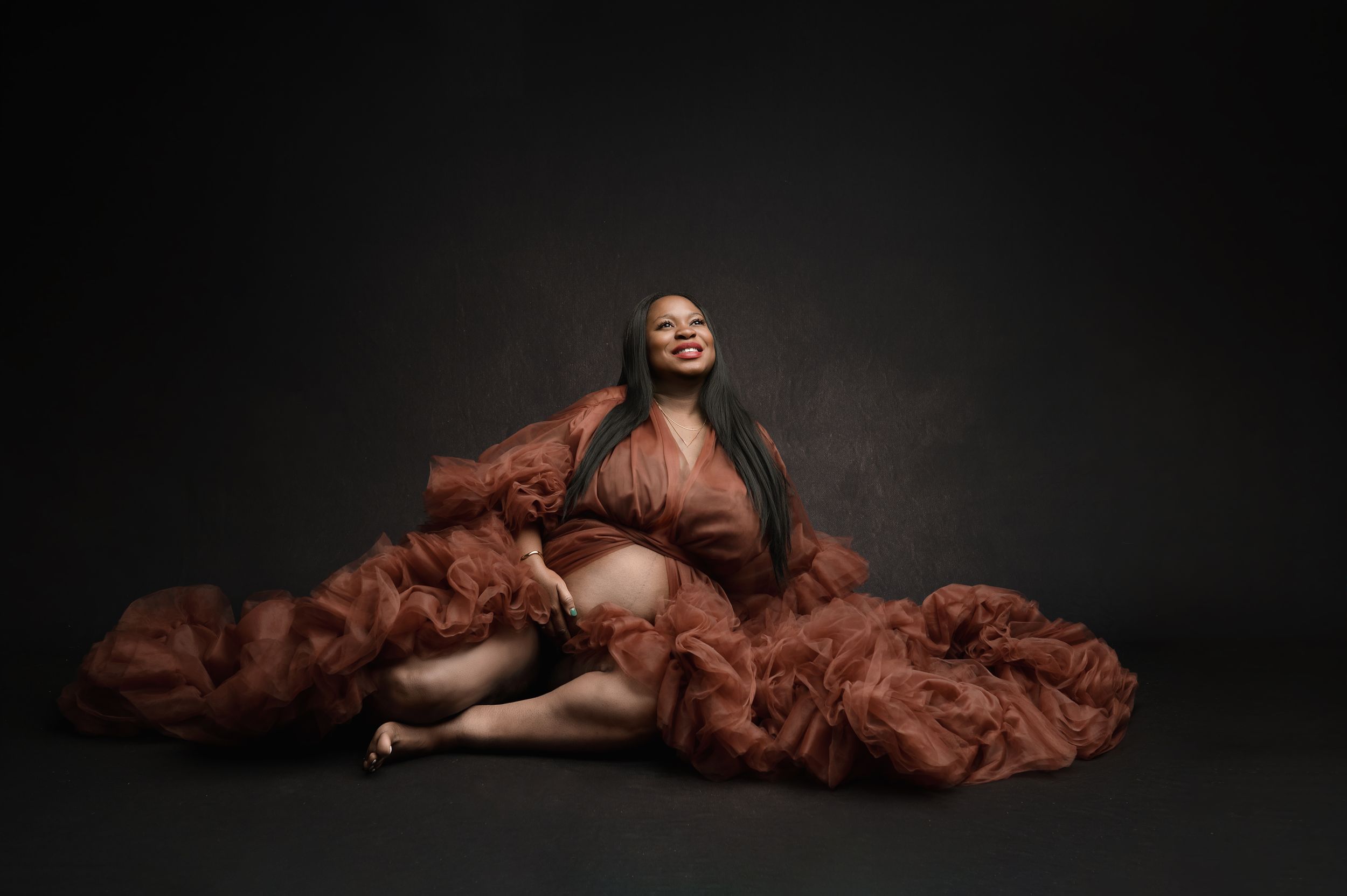 A series of dramatic artistic portraits showing a figure draped in flowing brown fabric against a dark background.