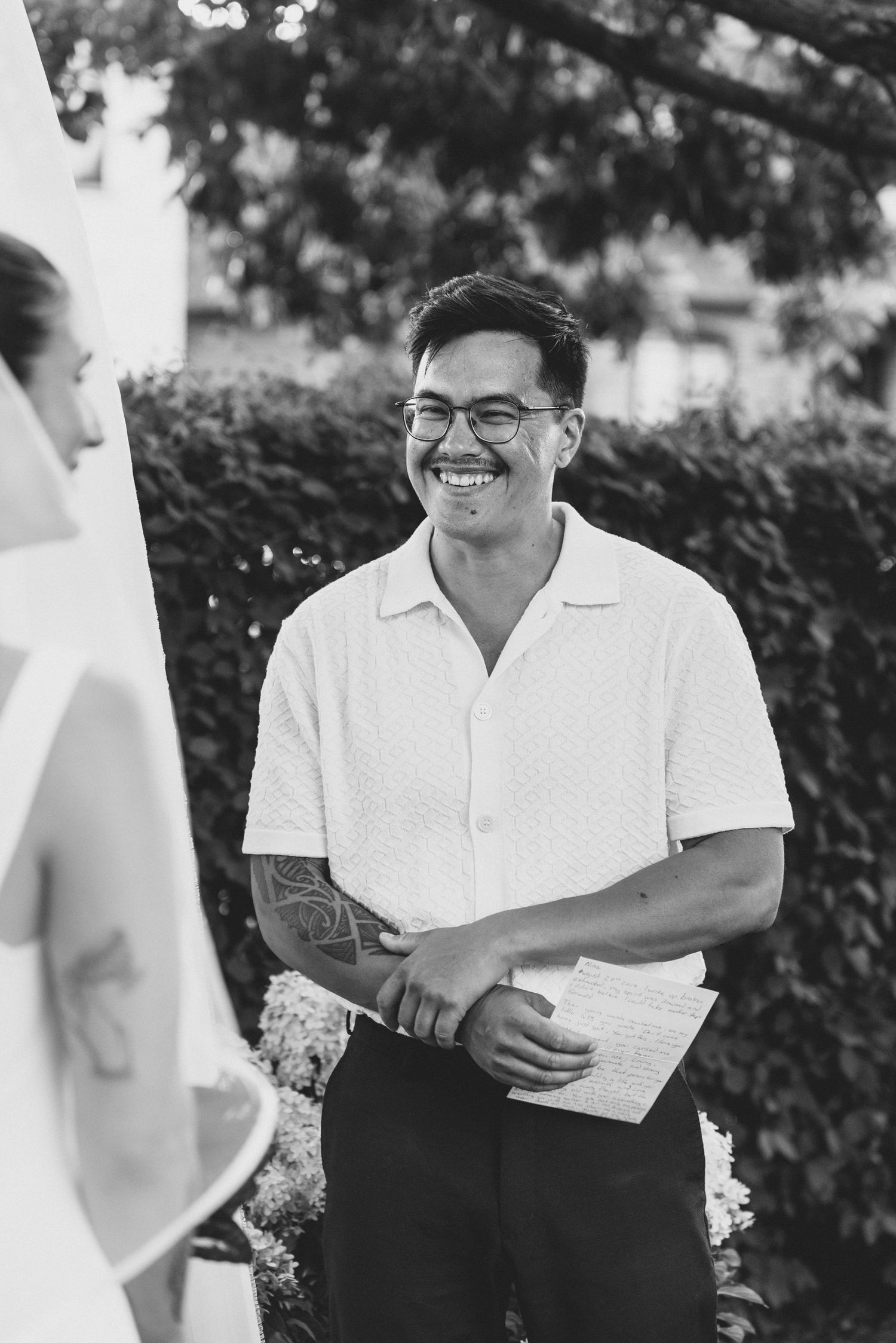 A person in a white polo shirt and dark pants laughs joyfully during an outdoor gathering.
