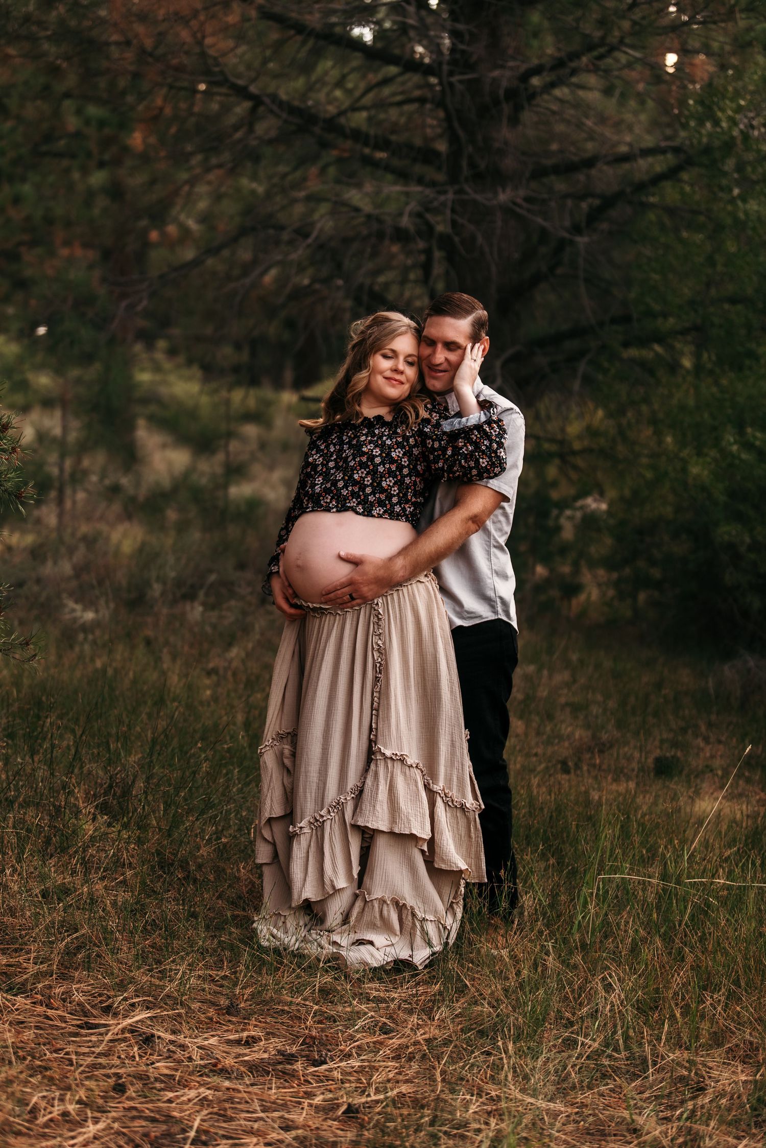 A couple embraces in a romantic outdoor setting with autumn foliage and natural lighting.