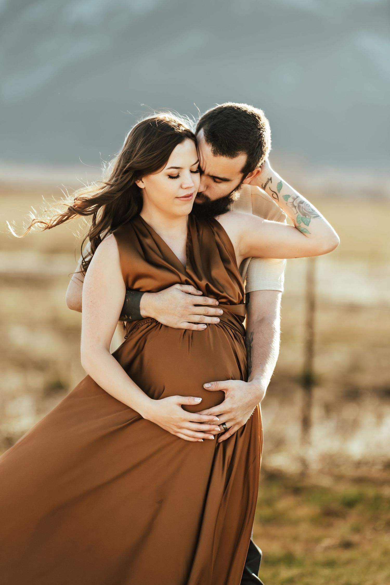 An intimate maternity portrait captured in warm sunlight with mountains in the distance.